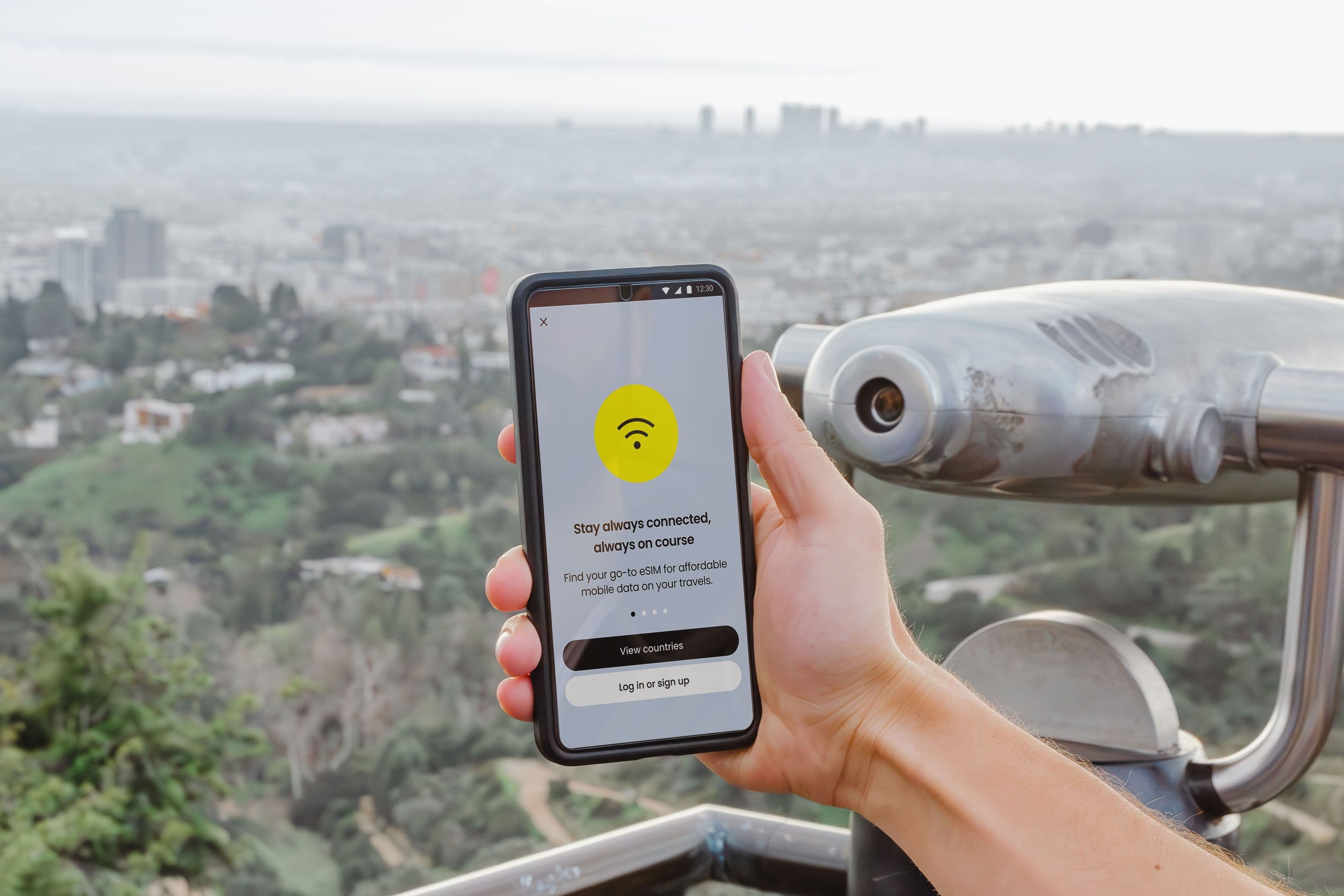 Smartphone displaying connectivity app with Los Angeles cityscape in the background.